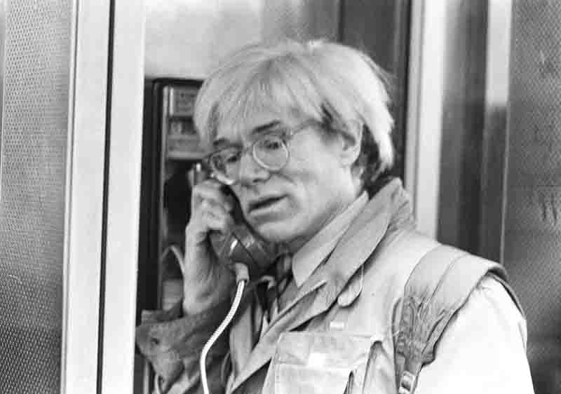 A famous photo of Andy Warhol shows him using a public phone in New York City, capturing a moment of his everyday life.