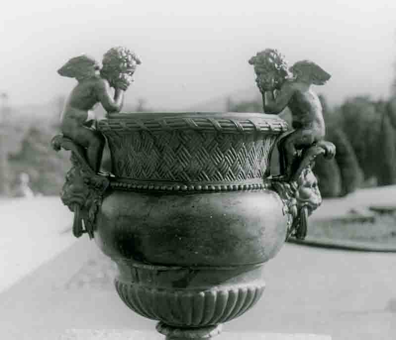 A black and white image featuring a vase adorned with two angel figures, highlighting their intricate details and serene expressions.