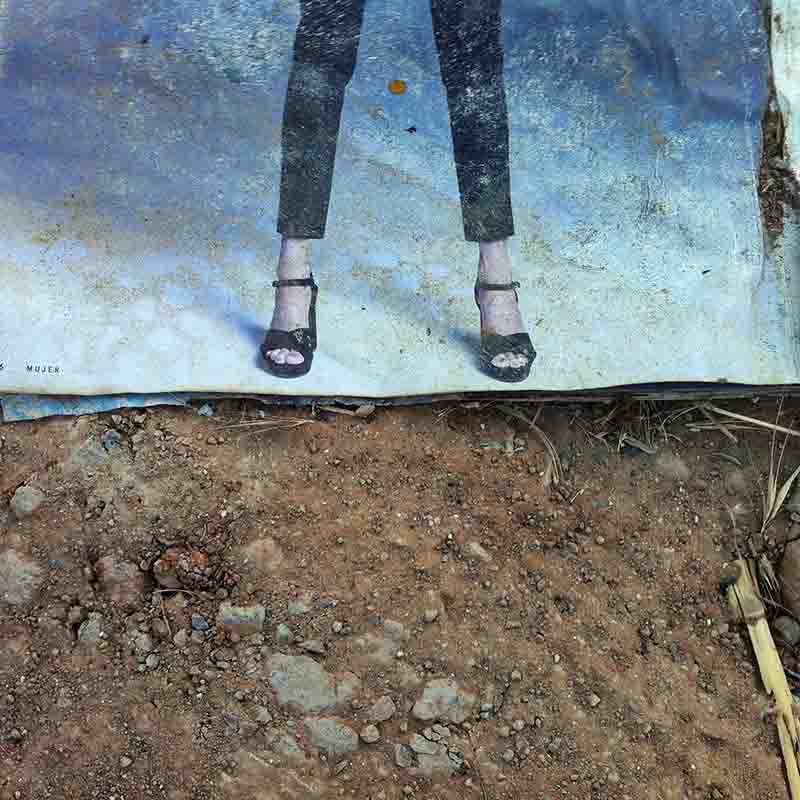 An fine art photo of a woman's legs on a poster lying on a weathered street to emphasize sustainability and progressiveness.