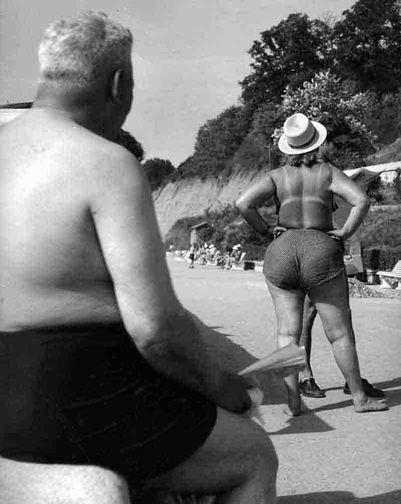 A man and woman in swimsuits enjoying a sunny day at the beach, surrounded by sand and ocean waves.